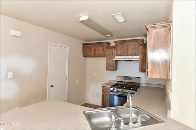 kitchen featuring visible vents, stainless steel gas stove, light countertops, under cabinet range hood, and a sink
