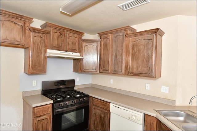kitchen with white dishwasher, a sink, black range with gas stovetop, under cabinet range hood, and visible vents