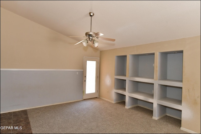 carpeted empty room featuring ceiling fan, baseboards, and lofted ceiling