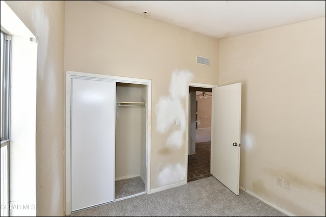 unfurnished bedroom featuring visible vents, carpet floors, baseboards, a closet, and lofted ceiling
