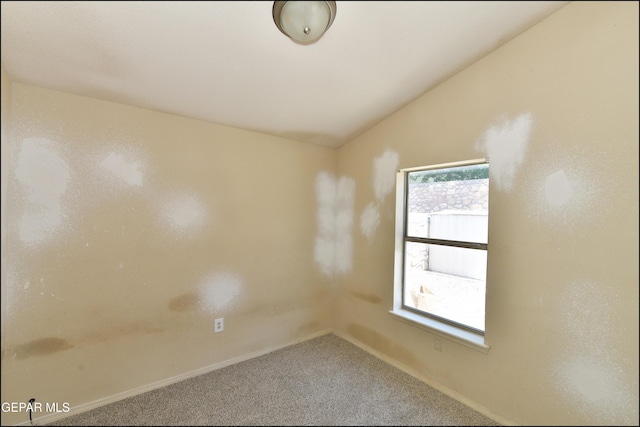 carpeted empty room with baseboards and lofted ceiling