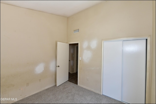 unfurnished bedroom featuring visible vents, carpet flooring, baseboards, and high vaulted ceiling
