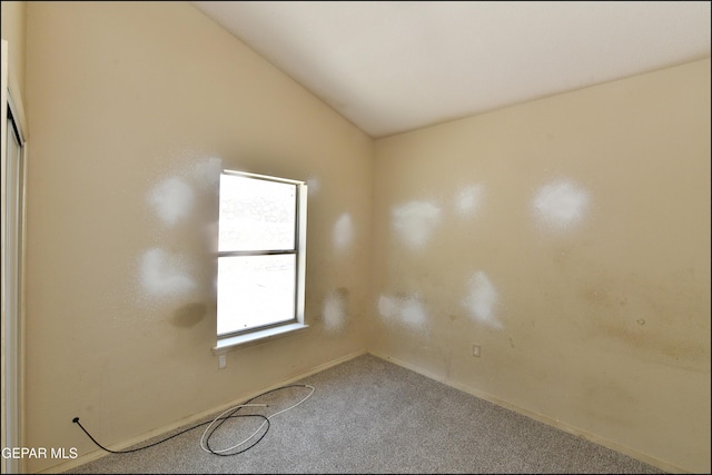 empty room featuring baseboards, carpet flooring, and lofted ceiling