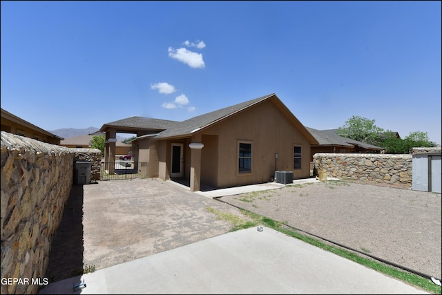 view of home's exterior with fence, stucco siding, a gate, central AC unit, and a patio area