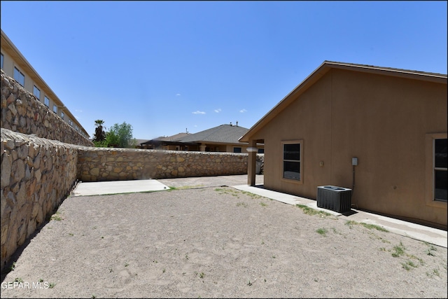view of yard with a fenced backyard, central AC unit, and a patio area
