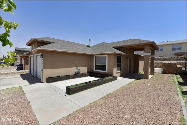 view of front of home with a garage, roof with shingles, stucco siding, and driveway