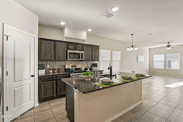 1021 Aerodyne Pl, El Paso, TX 79928 - kitchen featuring stainless steel appliances, dark brown cabinetry, ceiling fan, a sink, and dark stone counters