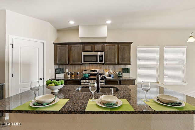 1021 Aerodyne Pl, El Paso, TX 79928 - kitchen with stainless steel appliances, dark brown cabinets, a sink, a center island with sink, and dark stone counters