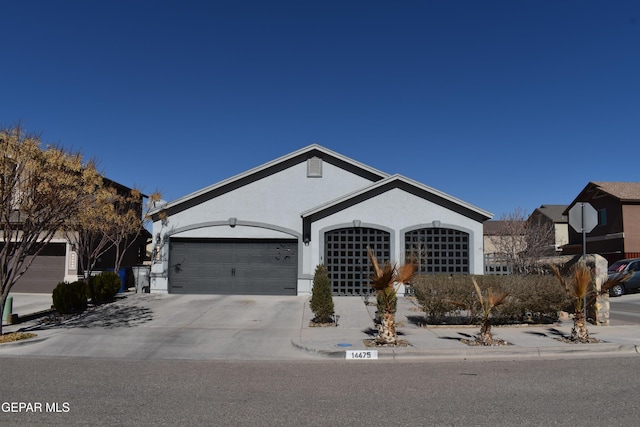 ranch-style house with stucco siding, an attached garage, and driveway