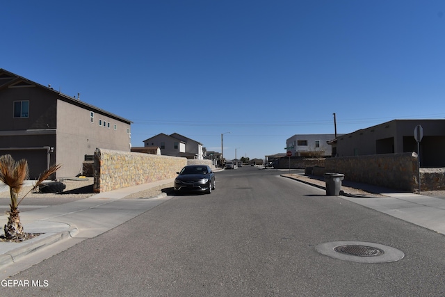 view of road featuring street lighting, curbs, sidewalks, and a residential view