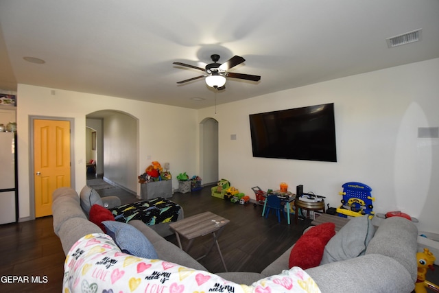 living room with arched walkways, a ceiling fan, visible vents, and wood finished floors