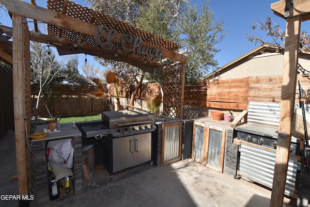 view of patio / terrace featuring area for grilling, an outdoor kitchen, a fenced backyard, and a pergola
