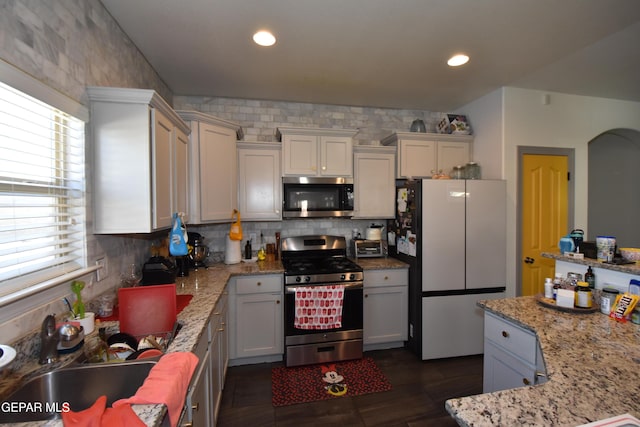 kitchen featuring light stone countertops, recessed lighting, tasteful backsplash, a sink, and appliances with stainless steel finishes