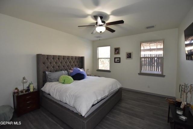 bedroom with visible vents, dark wood-type flooring, multiple windows, and ceiling fan