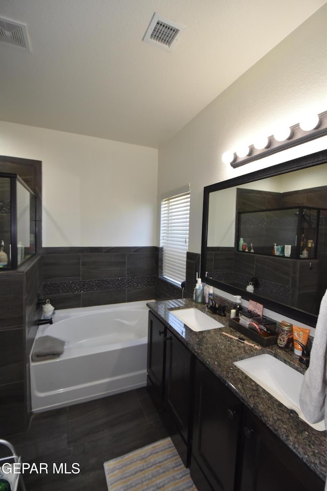 full bathroom featuring visible vents, a sink, and a garden tub