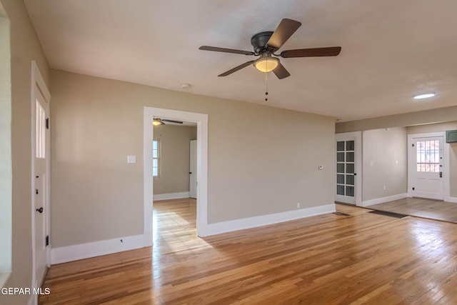 empty room featuring a ceiling fan, baseboards, and light wood-type flooring
