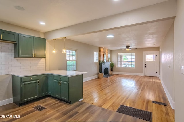 kitchen featuring visible vents, decorative backsplash, a peninsula, a healthy amount of sunlight, and green cabinets