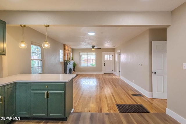 kitchen with light wood-type flooring, green cabinets, a peninsula, and visible vents