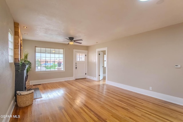 unfurnished living room with baseboards, visible vents, ceiling fan, and light wood-type flooring