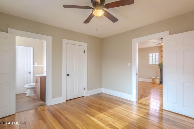 unfurnished bedroom with a ceiling fan, baseboards, light wood-style flooring, and ensuite bath