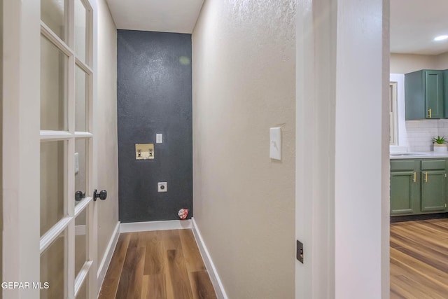 corridor with baseboards, a textured wall, and wood finished floors
