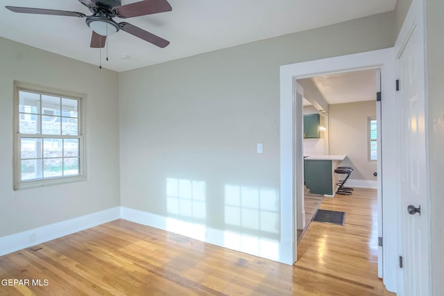unfurnished room featuring baseboards, a ceiling fan, wood finished floors, and visible vents