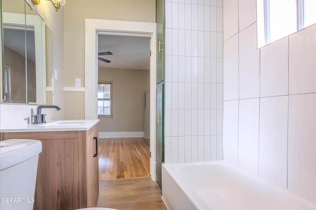 bathroom featuring vanity, tub / shower combination, wood finished floors, toilet, and baseboards