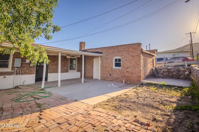 back of property featuring ceiling fan, a chimney, a patio area, brick siding, and fence