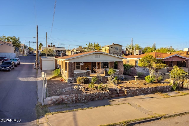 bungalow-style house with a porch, driveway, a residential view, brick siding, and fence