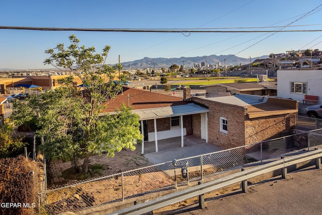 ranch-style house featuring a fenced backyard, a mountain view, a patio area, and brick siding