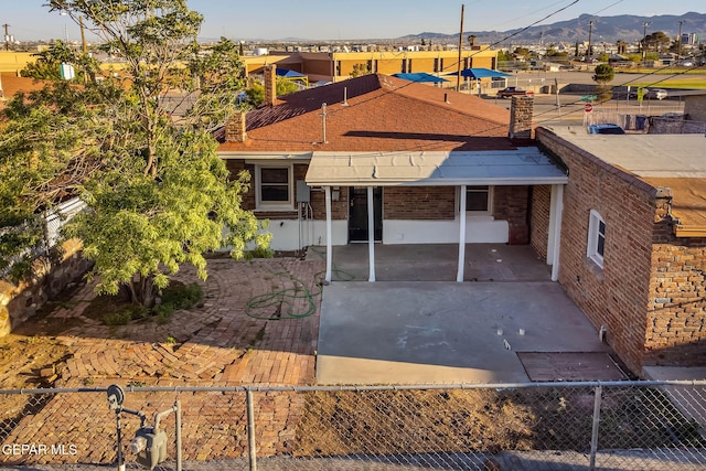 ranch-style house featuring brick siding, a mountain view, and fence