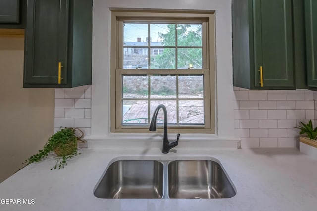 kitchen featuring a sink, light countertops, green cabinetry, and decorative backsplash