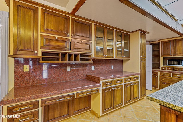 624 Mount Cristo Rey Ln, El Paso, TX 79922 - kitchen with light tile patterned floors, decorative backsplash, glass insert cabinets, and brown cabinetry