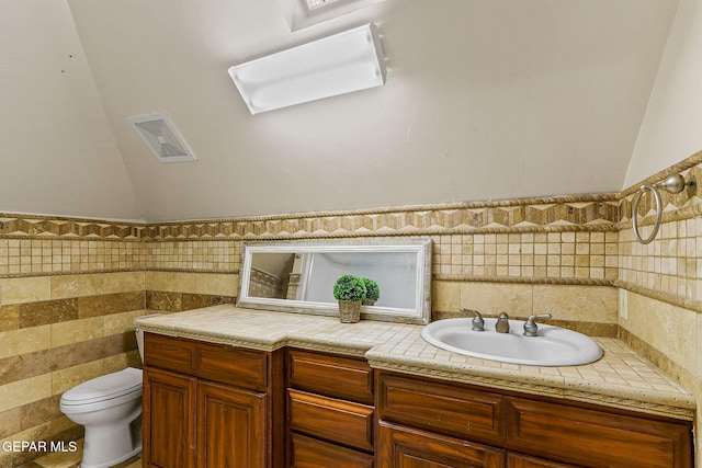 624 Mount Cristo Rey Ln, El Paso, TX 79922 - bathroom featuring tile walls, toilet, vanity, and vaulted ceiling