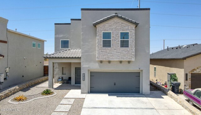 view of front of house with a tile roof, stone siding, a garage, stucco siding, and driveway