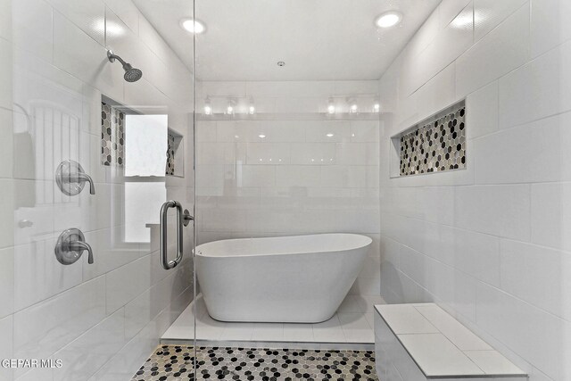 bathroom with tile patterned floors, tile walls, a tile shower, and a soaking tub