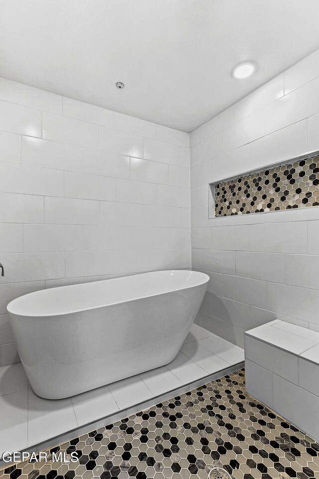 bathroom with a freestanding tub and tile walls
