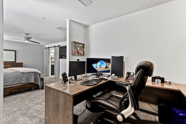 carpeted office with ceiling fan, visible vents, and a barn door