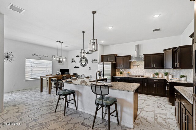 kitchen featuring visible vents, marble finish floor, wall chimney exhaust hood, and stainless steel appliances