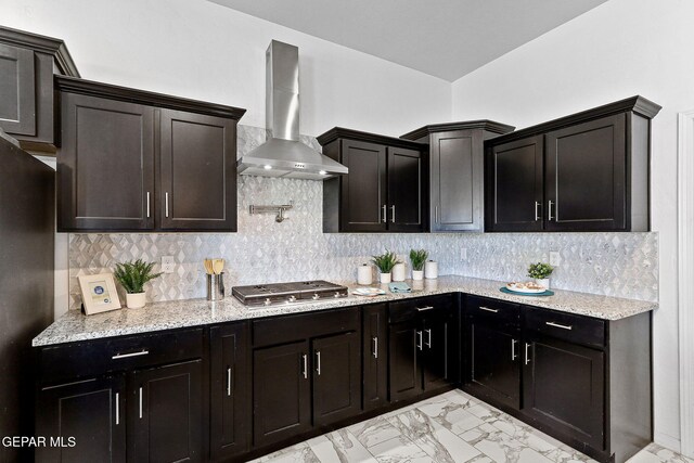 kitchen with backsplash, light stone counters, marble finish floor, stainless steel appliances, and wall chimney exhaust hood