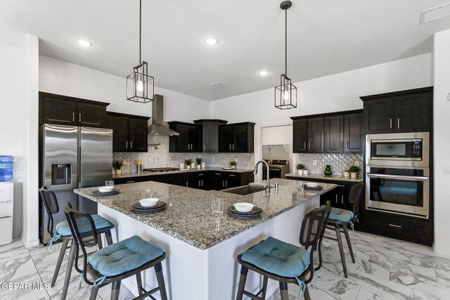 kitchen featuring marble finish floor, range hood, a spacious island, a sink, and appliances with stainless steel finishes
