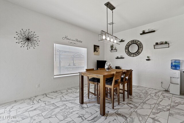 dining room featuring an inviting chandelier, baseboards, and marble finish floor