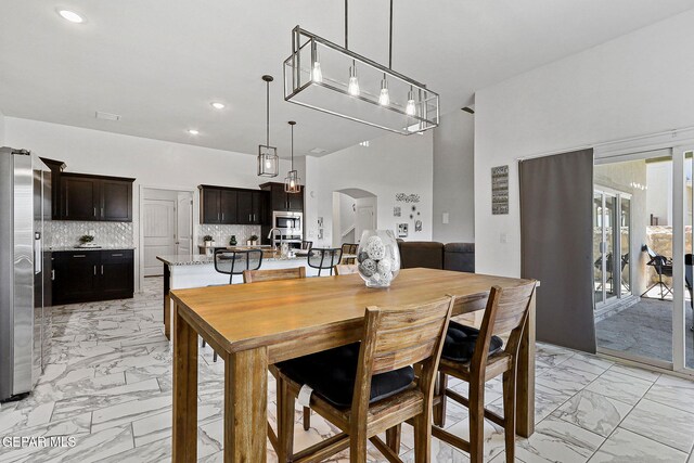 dining room featuring recessed lighting, arched walkways, and marble finish floor