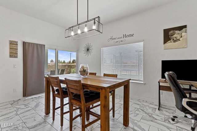 dining area featuring an inviting chandelier and marble finish floor