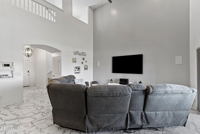 living room with arched walkways, marble finish floor, and a high ceiling
