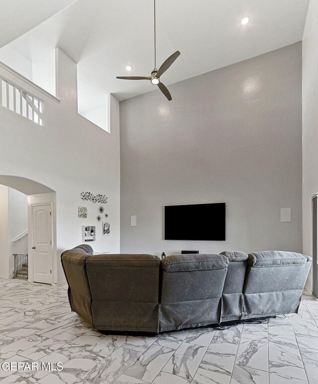 living area featuring a high ceiling, arched walkways, marble finish floor, a ceiling fan, and recessed lighting