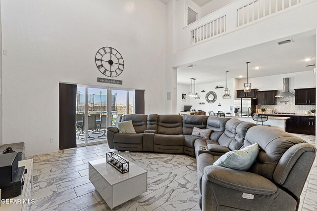 living area featuring a towering ceiling, visible vents, and marble finish floor