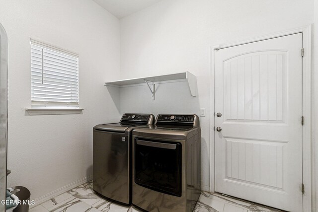 clothes washing area featuring laundry area, washer and clothes dryer, marble finish floor, and baseboards