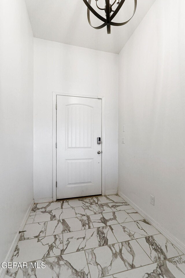doorway with baseboards and marble finish floor