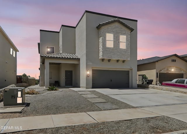 view of front of home with a tiled roof, a garage, concrete driveway, and stucco siding